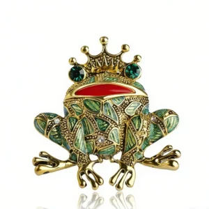 Broche grenouille couronnée aux yeux verts, motifs verts et dorés sur fond blanc