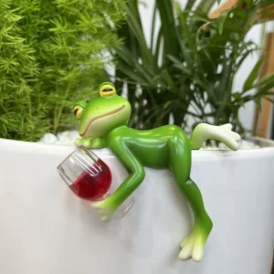 Grenouille verte allongée sur le bord d’un pot avec un verre rouge
