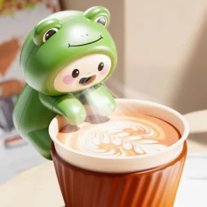 Mini ventilateur vert en forme de grenouille installé au bord d’une tasse de café