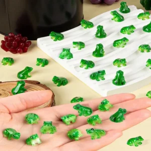 Mini figurines de grenouilles vertes en résine présentées dans une main et sur une surface claire