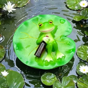 Figurine de grenouille verte tenant une bouteille sombre sur une feuille de nénuphar, présentée sur l’eau