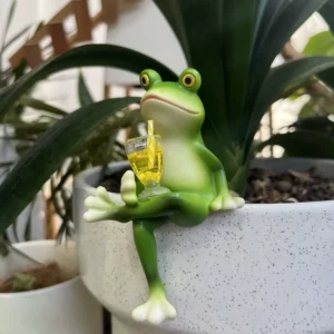 Grenouille verte assise au bord d’un pot avec un petit verre jaune
